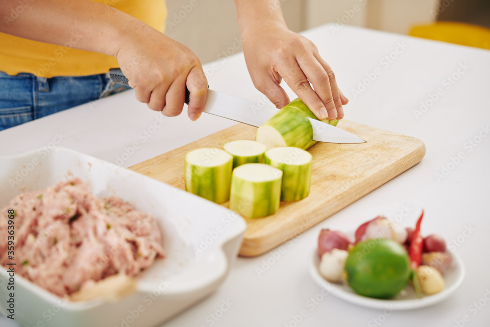Hands of woman cutting zuccini with sharp knife on wooden board Hands of woman cutting zuccini with sharp knife on wooden board