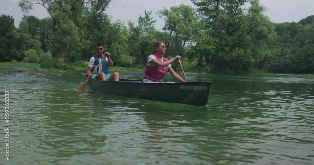 Young Happy Couple Paddling Kayak on the Beautiful River or Lake Young Happy Couple Paddling Kayak on the Beautiful River or Lake