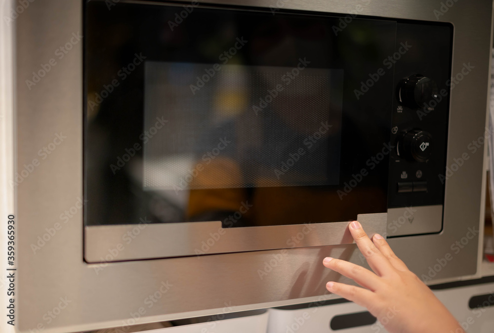Female hand Opening Or Closing modern electric oven prepare to cooking in the modern kitchen. New interior kitchen concept. Female hand Opening Or Closing modern electric oven prepare to cooking in the modern kitchen. New interior kitchen concept.