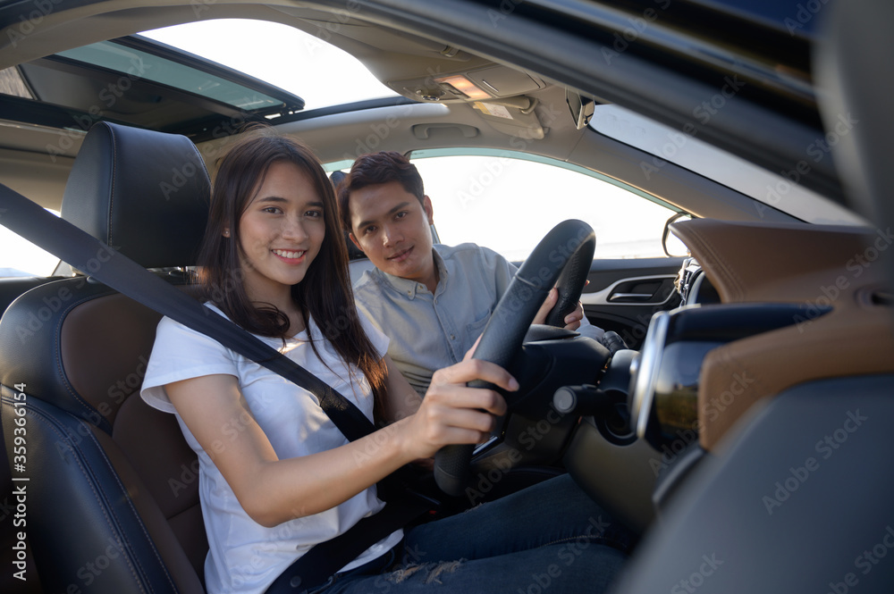 Young couple in his car, happy to drive on a country road. Happy young women and young men in car
