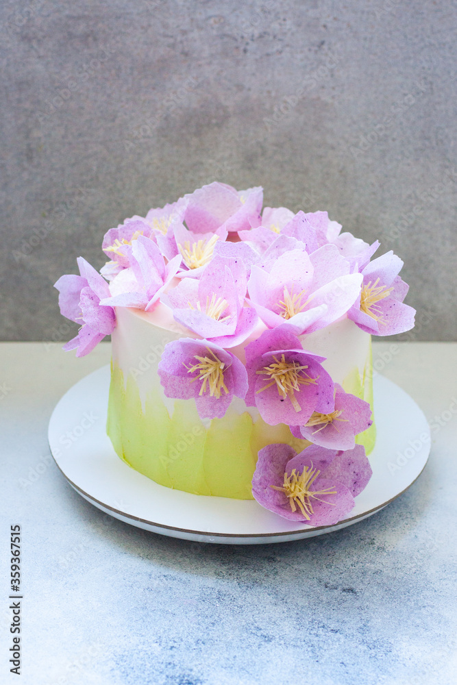 Tender green birthday cake with purple and pink paper flowers on grey background. Tender green birthday cake with purple and pink paper flowers on grey background.