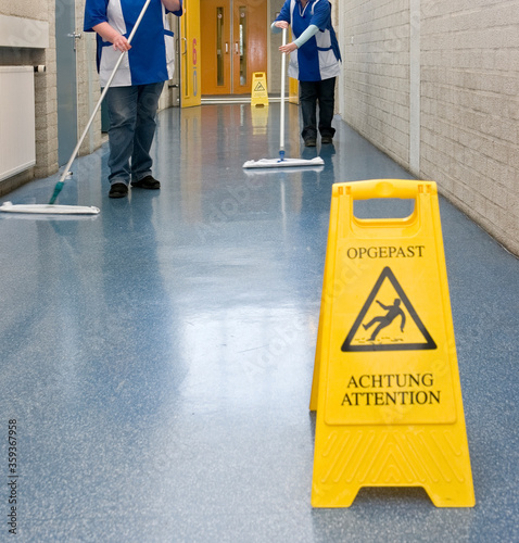 Sign wet floor. Cleaning ladies. Corridor.