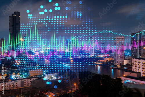 Stock market graph hologram, night panorama city view of Bangkok, popular location to gain financial education in Asia. The concept of international research. Double exposure.