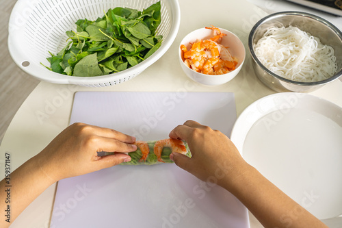 Woman wrapping Vietnamese salad shrimp rolls- Goi Cuon