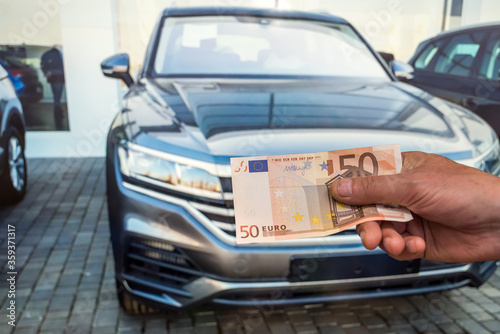 concept of buying a new car. male hand holds a euro for a successful deal