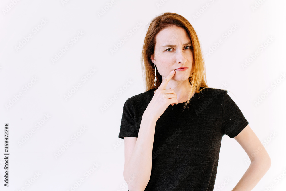 The thinking girl is on the white background. The girl with a finger at the mouth The thinking girl is on the white background. The girl with a finger at the mouth