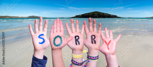 Children Hands Building Colorful English Word Sorry. Ocean And Beach As Background