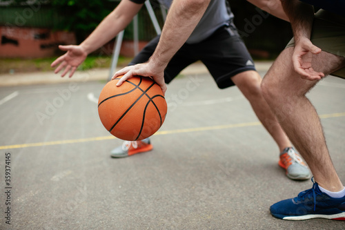 Close up of hands holding ball. Friends playing basketball in the park.  © JustLife