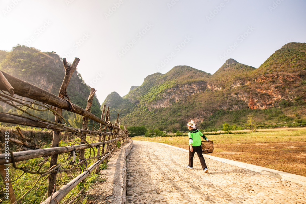 A femle Chinese farmer walking in the meadow of the mountains.