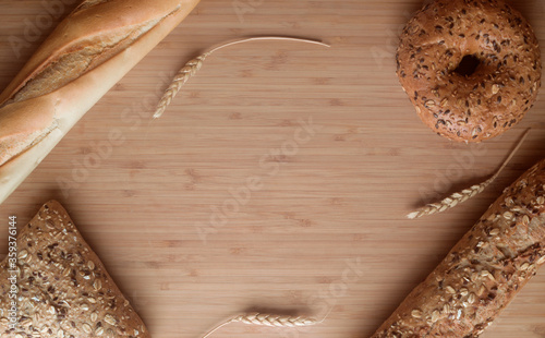 Different types of bread, fresh pastries in the bakery. Bread with sesame seeds, cereals, seeds. Different forms and types of rolls.wooden board. Place for text or logo, discounts