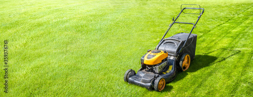 Lawn mower on fresh green lawn, freshly cut grass on summer sunny day, banner