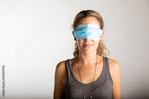 young woman wearing the surgical mask incorrectly by  covering her eyes.