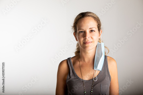 young woman wearing the surgical mask on the ear to show her smiling face.