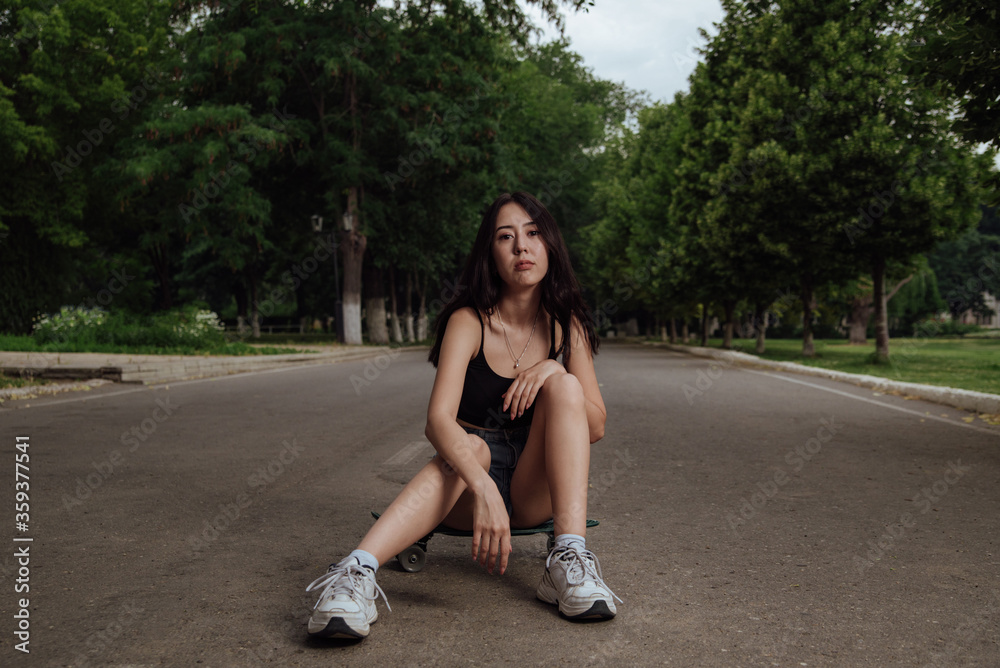Young girl sitting on a skateboard in the city Young girl sitting on a skateboard in the city