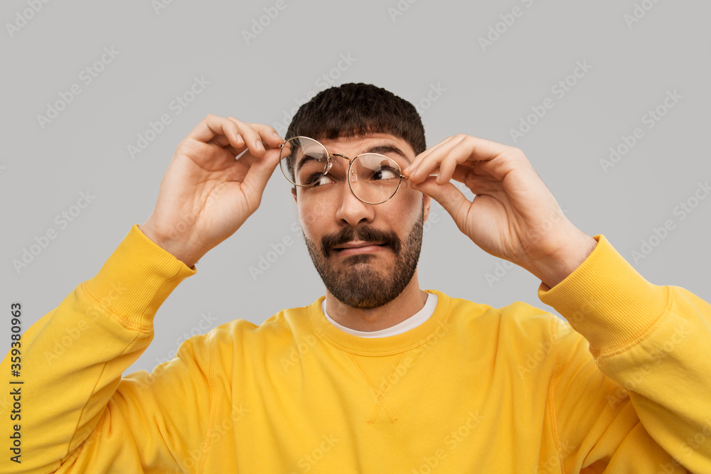 vision and people concept - goofy young man in glasses and yellow sweatshirt over grey background vision and people concept - goofy young man in glasses and yellow sweatshirt over grey background