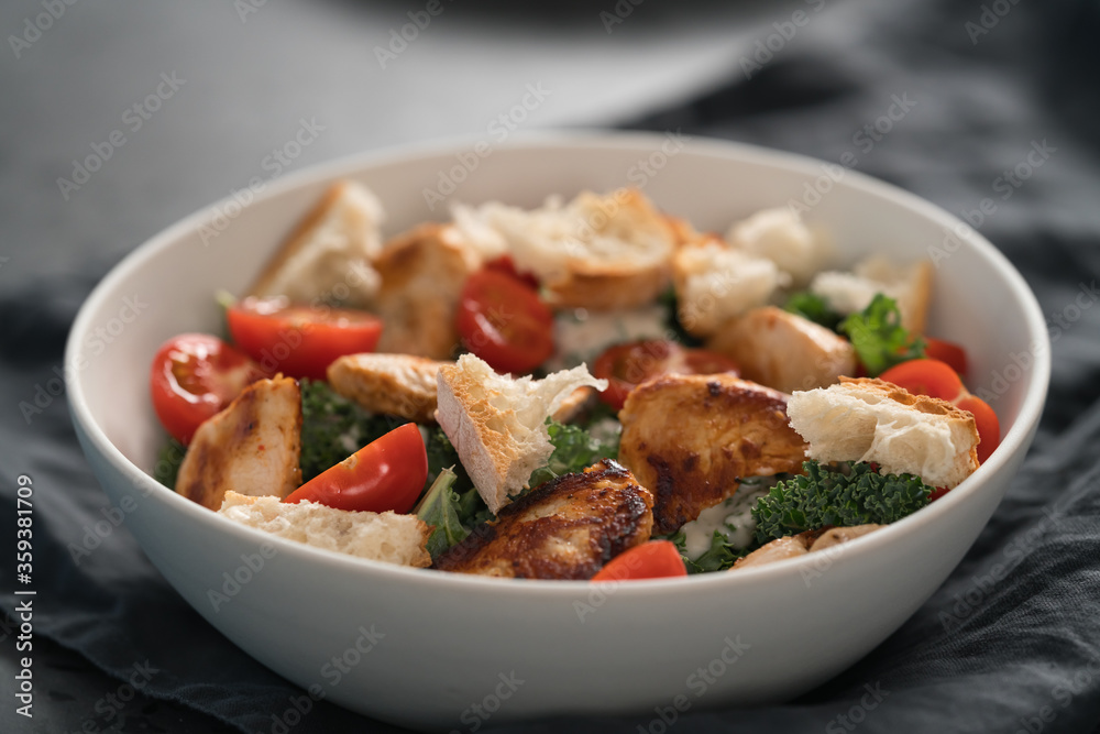 Caesar salad alternative with kale and turkey in white bowl Caesar salad alternative with kale and turkey in white bowl