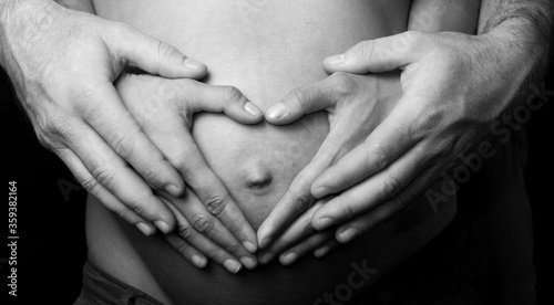 Pregnant woman belly with heart hands