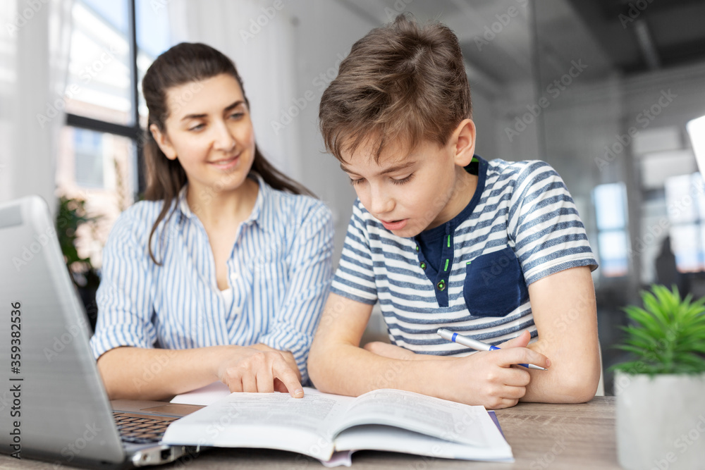 education, family and homework concept - smiling mother and son with book writing to notebook at home education, family and homework concept - smiling mother and son with book writing to notebook at home