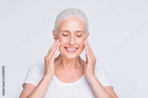 Close-up portrait of her she nice-looking attractive groomed cheerful cheery gentle gray-haired middle aged lady washing cleansing moisturizing elastic skin isolated over light white grey background