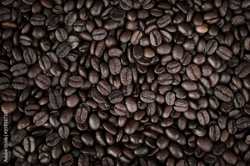 Mixture of different kinds of fresh roasted brown coffee beans in dark tones
