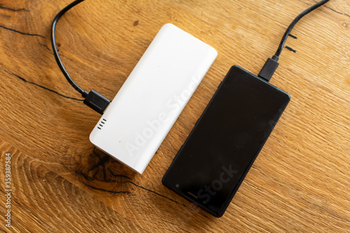 Mobile Phone and a USB Power Bank on a wooden Table to charge the moblie device