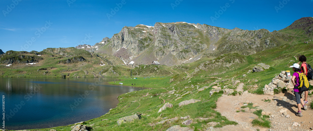 two hiker women in path of the Ayous lake in french Pyrenees mountains