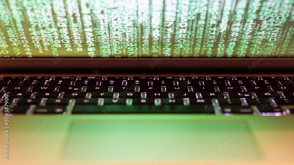 View of an partly open Laptop with a green matrix on the screen, shining on the keyboard