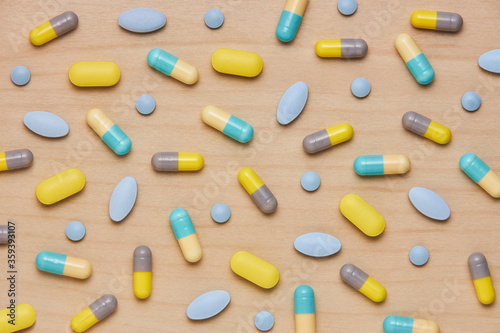 colorful tablets and capsules on wooden background. Health care concept
