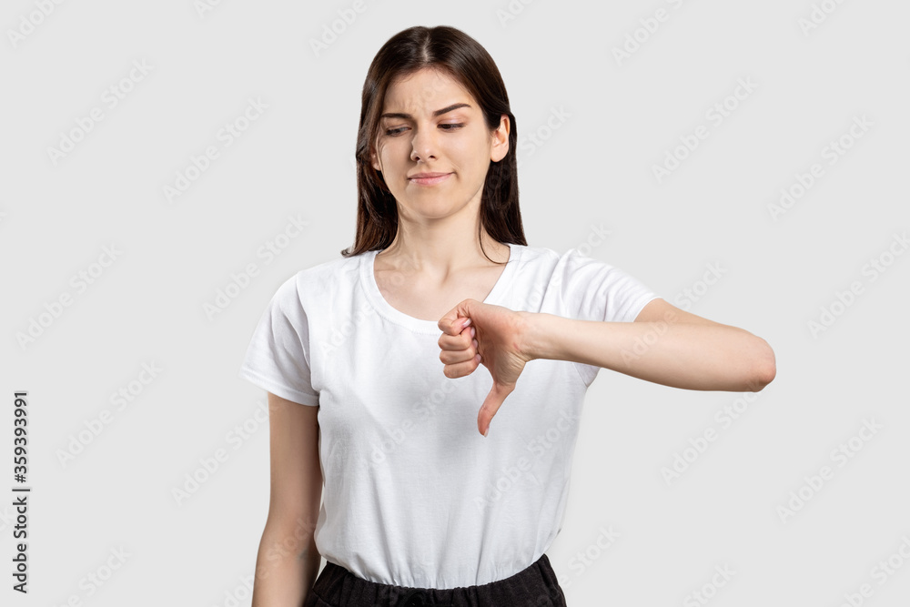 Dislike gesture. Not cool. Criticizing woman showing thumb down isolated on neutral background. Dislike gesture. Not cool. Criticizing woman showing thumb down isolated on neutral background.