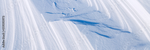 Snow texture. Wind sculpted patterns on snow surface. Wind in the tundra and in the mountains on the surface of the snow sculpts patterns and ridges. Arctic, Polar region. Winter panoramic background. photo