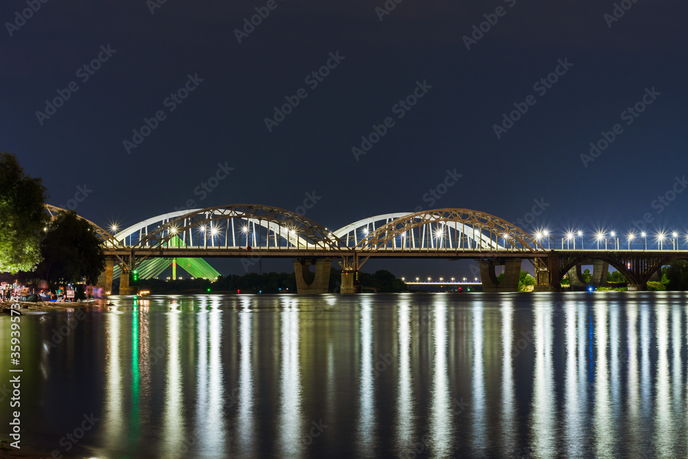 Evening view of Kyiv, night city lights, bridge over the river, panorama of the capital of Ukraine