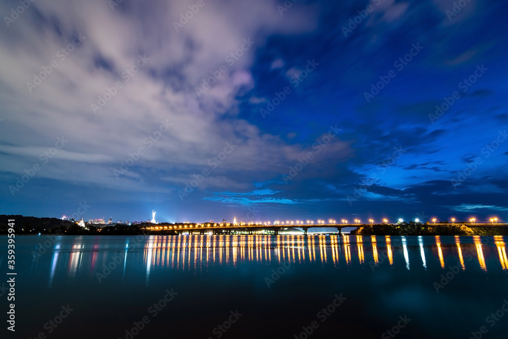 Fototapeta premium Evening view of Kyiv, night city lights, bridge over the river, panorama of the capital of Ukraine