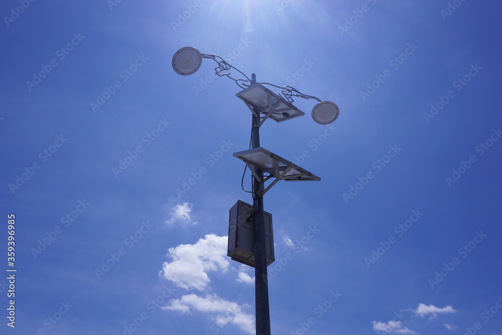 Up-risen angle of the lamp with power solar panel and on blue sky and cloud as background.  Alternative clean green energy concept with the midday light in Thailand.