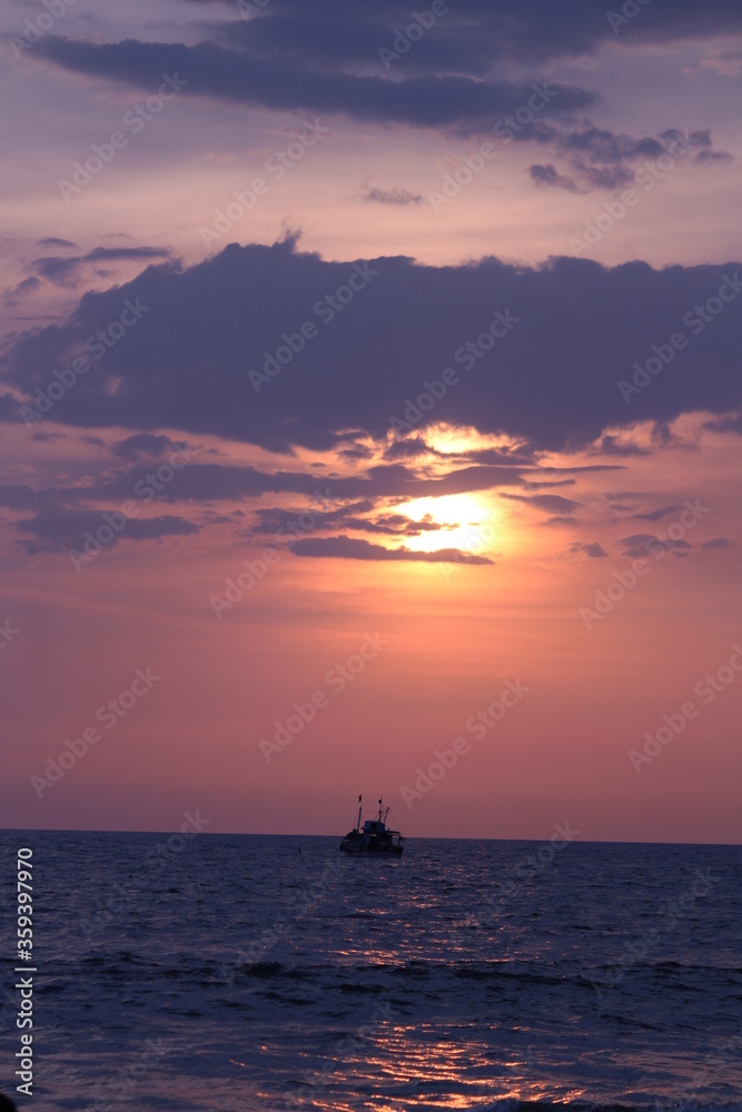 Ship sailing in the ocean  with sunset and rays of the sun.