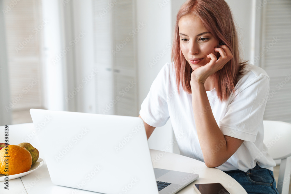 Photo of serious woman working with laptop while sitting at table Photo of serious woman working with laptop while sitting at table