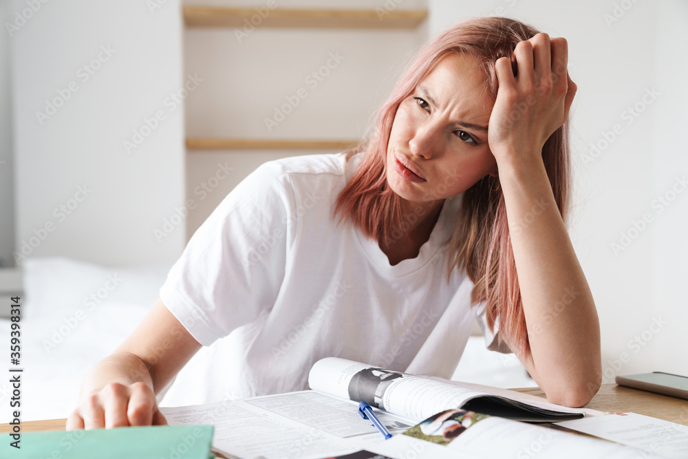 Image of tired caucasian woman doing homework with exercise books Image of tired caucasian woman doing homework with exercise books