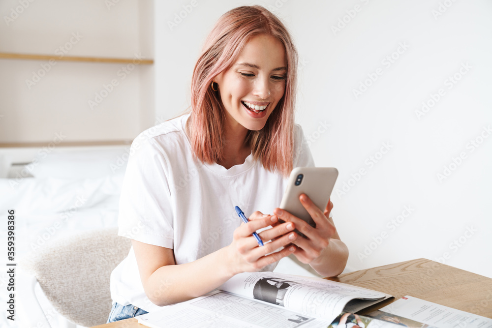 Image of woman using smartphone while doing homework with exercise books Image of woman using smartphone while doing homework with exercise books