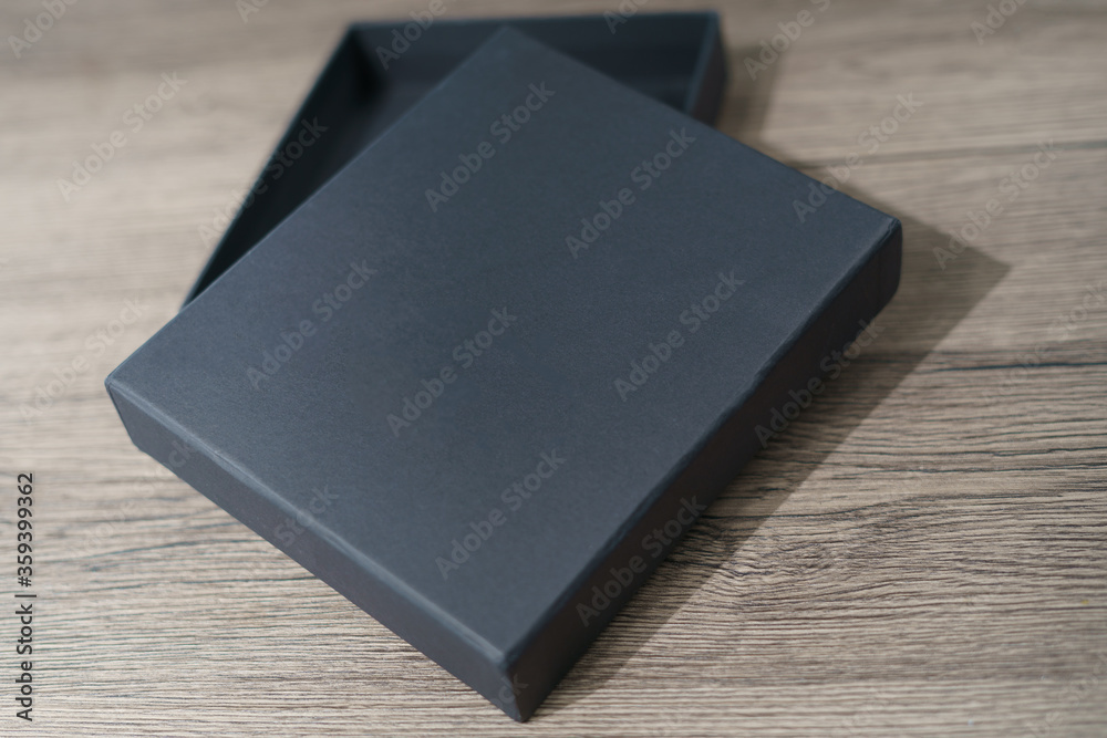 Opened black cardboard box on a brown wooden table. Opened black cardboard box on a brown wooden table.
