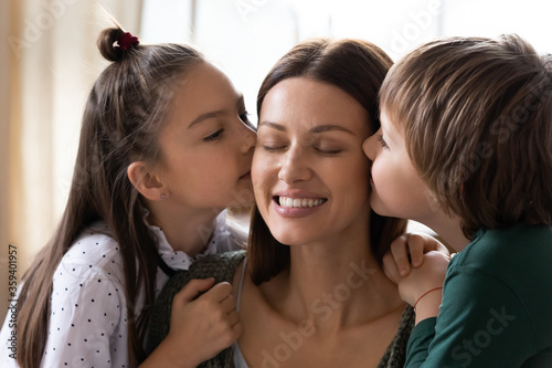 Cute children, adorable daughter and little son kissing smiling mother on cheeks close up, pretty girl and boy congratulating happy mum with birthday, women or mothers day, enjoying tender moment