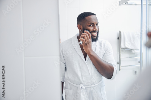 Positive delighted male person correcting his beard