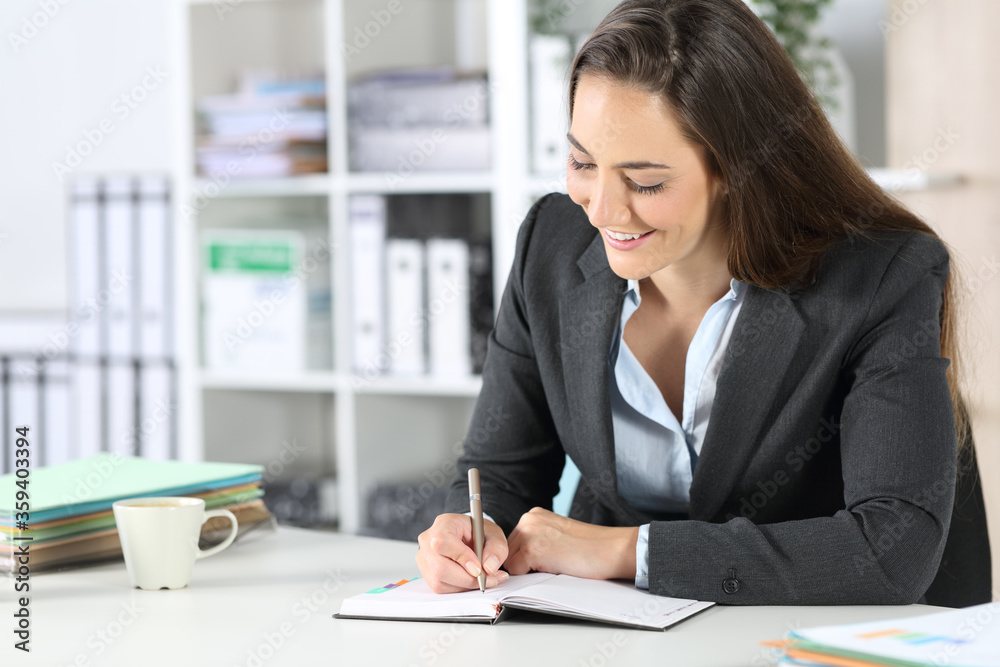 Happy executive writing notes on agenda at office Happy executive writing notes on agenda at office
