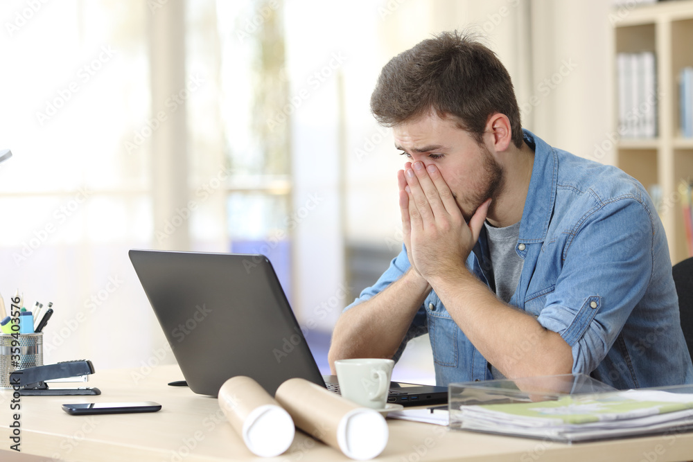 Worried entrepreneur looking at laptop at office Worried entrepreneur looking at laptop at office