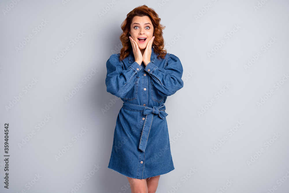 Photo of attractive funny crazy ginger curly lady holding arms on cheeks see sale discount advertisement wear casual blue denim short dress isolated grey color background Photo of attractive funny crazy ginger curly lady holding arms on cheeks see sale discount advertisement wear casual blue denim short dress isolated grey color background