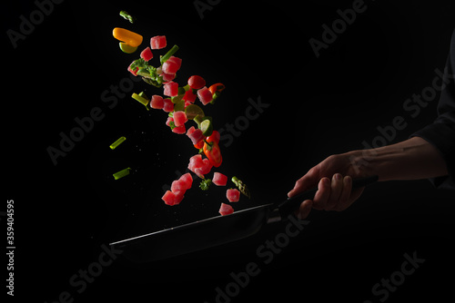 Pieces of tuna fish with vegetables in a pan, freezing in motion, frying, restaurant business