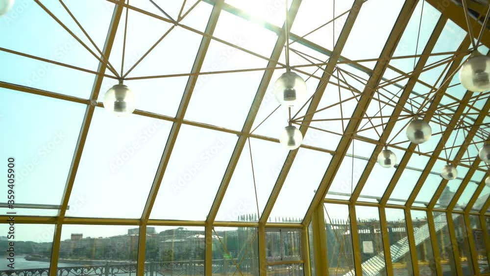 Long glass tunnel on the pedestrian bridge. Glass roof. The camera is in motion Long glass tunnel on the pedestrian bridge. Glass roof. The camera is in motion