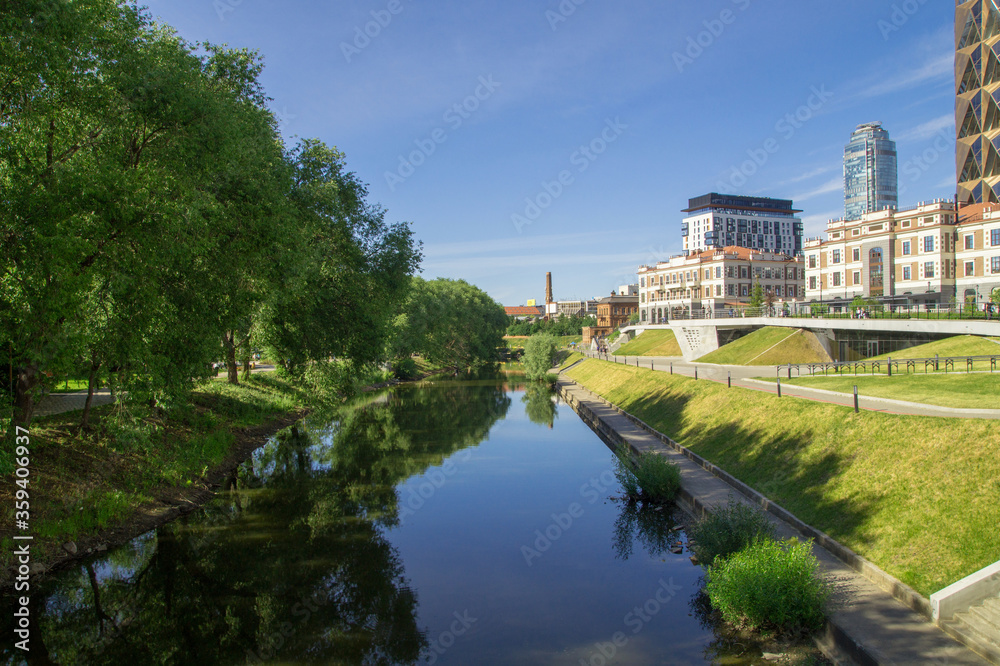 Buildings reflected in the water of a city park in sunny weather