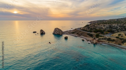 Aerial Bird's eye view of Petra tou Romiou, aka Aphrodite's rock a famous tourist travel destination landmark in Paphos, Cyprus. The sea bay of goddess Afroditi birthplace at sunset from above. photo