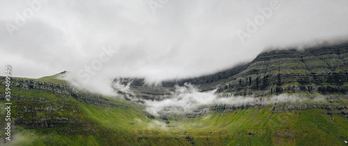 Faroe Islands aerial landscape photography with outstanding green mountains with thick clouds. 