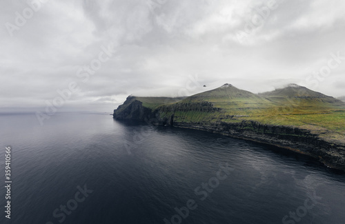 Spectacular aerial panorama with deep blue ocean and green cliffs of Faroe Islands. 