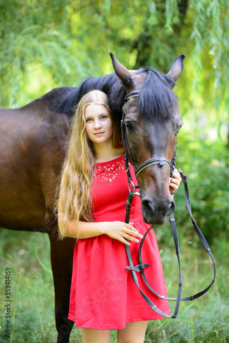 outdoor portrait of young beautiful woman with horse. Against the background of a tree